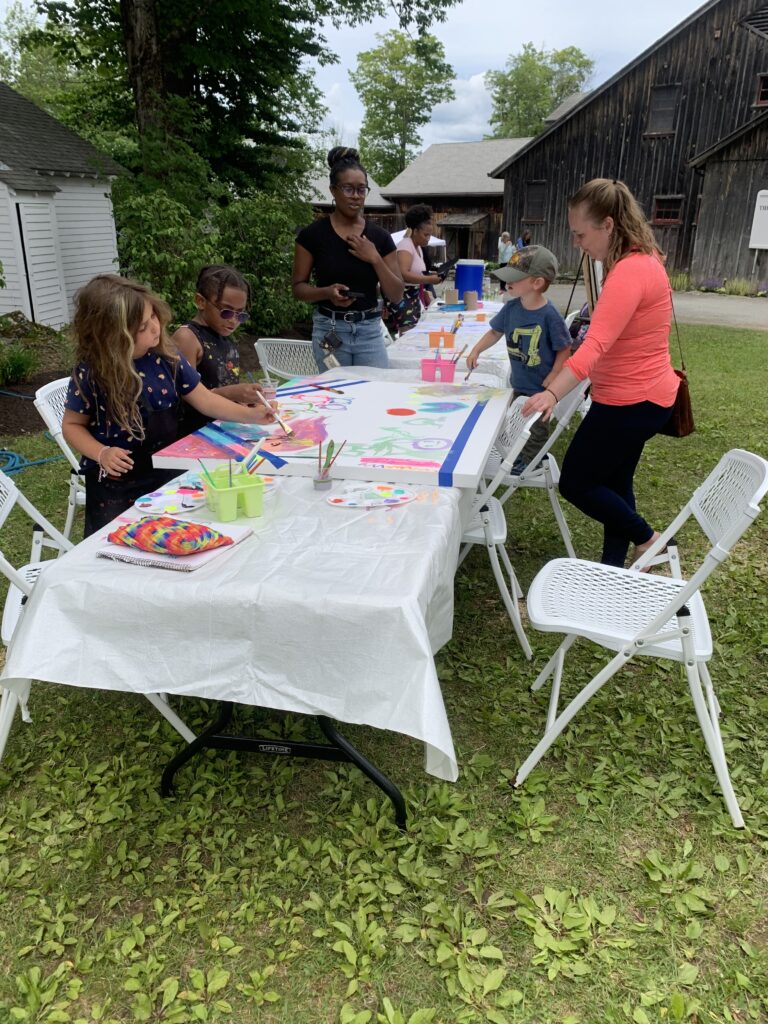 Kids sit around a table with arts and crafts.